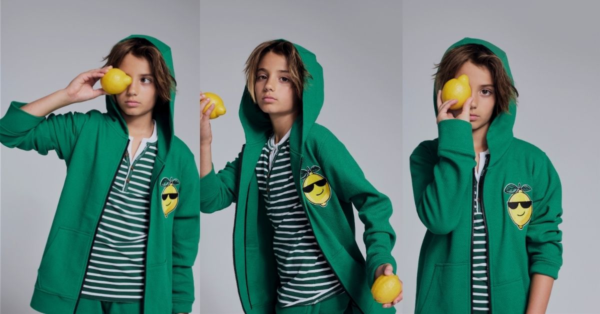 Three views of a child modeling a bright green zip-up hoodie over a green and white striped shirt, holding yellow lemons against a plain gray studio background.