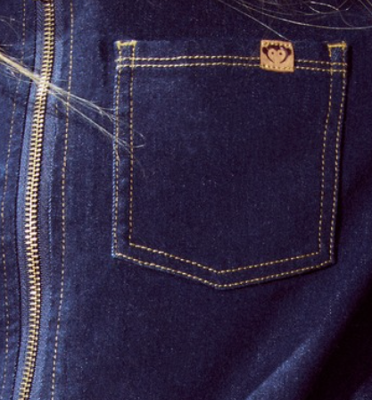 Close-up of a blue denim pocket with a brand logo on a dark background