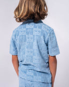 Denim blue Resort Terry Shirt featuring playful palm tree and smiley face designs, perfect for stylish summer adventures.