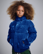 Child wearing a blue puffer jacket against a gray background