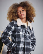 Person wearing a plaid jacket with a white collar against a gray background