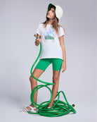 A girl wearing the Tropical Green Biker Short with a hose in her hands, styled for summer adventures.