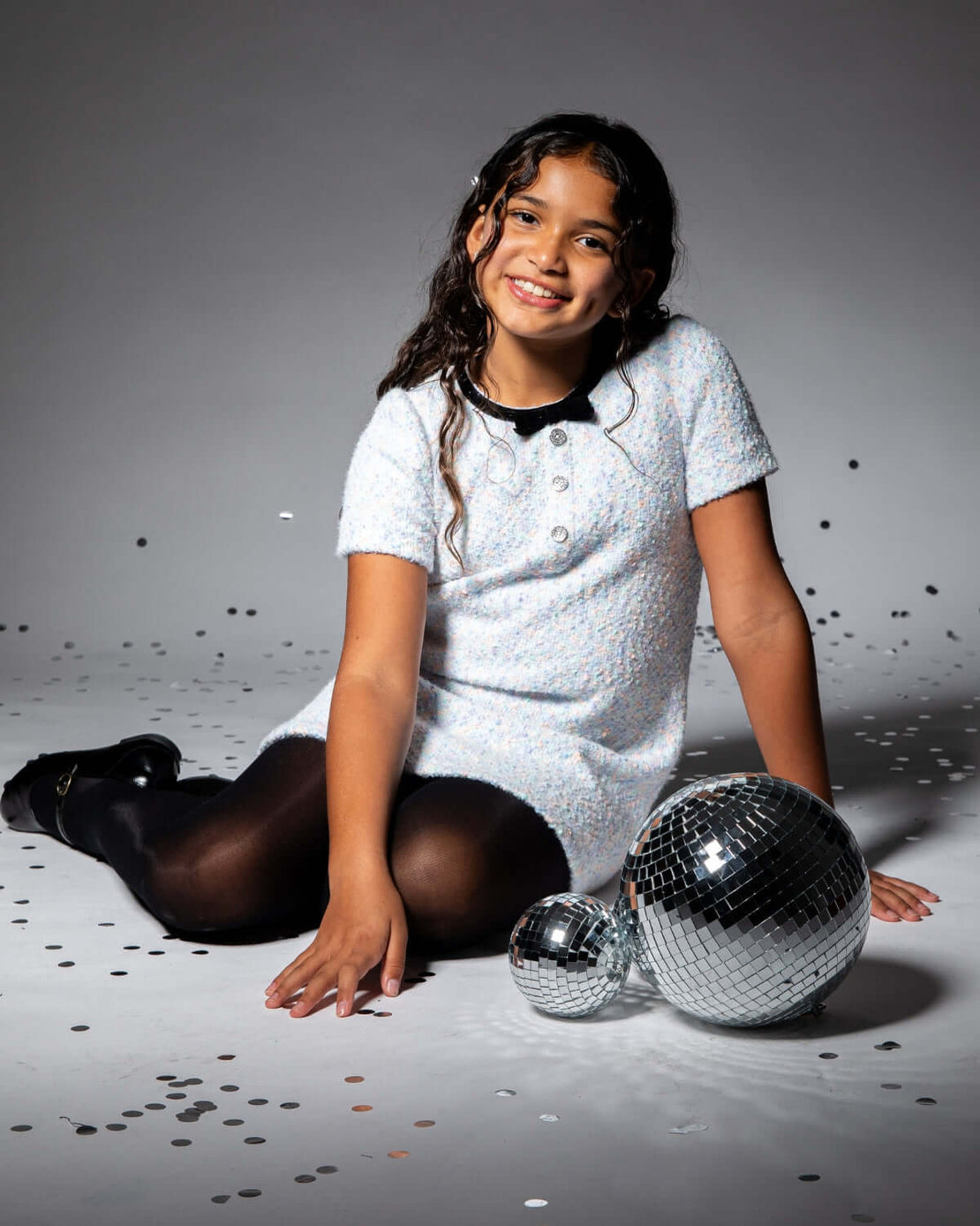 a girl sitting on the floor with disco balls