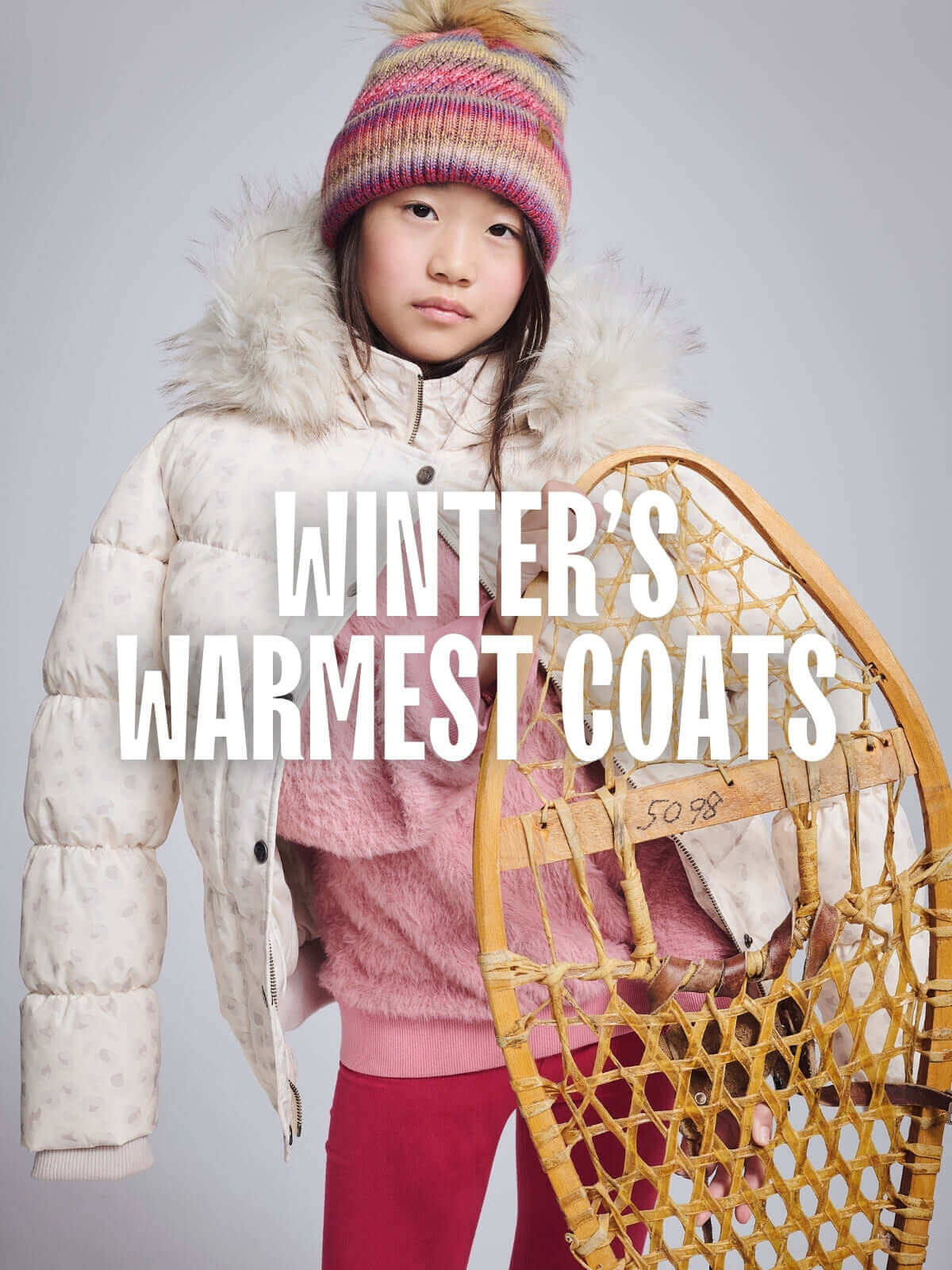A child in a white winter coat and colorful hat, showcasing high-quality kids clothing for warmth and style.