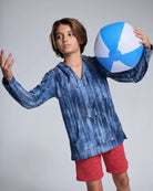 Boy wearing a blue hoodie and Washed Red Preston Short, holding a beach ball, ready for summer fun.