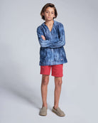 A child wearing a stylish Waterfall Terry Baja Pullover with red shorts, showcasing the unique tie dye design.
