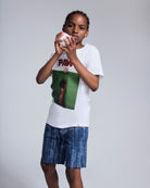 Child wearing a graphic tee and Waterfall Preston Short, ready to play with a baseball.