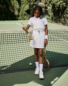 Young girl on a tennis court holding a racket and a bag