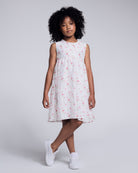 Girl in White Rose Empire Dress featuring floral print and front bow, perfect for sunny days and special moments.