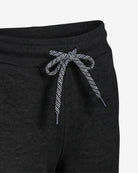 Close-up of dark charcoal gray sweatpants with a black and white patterned drawstring bow at the waistband, shown against a plain light background.