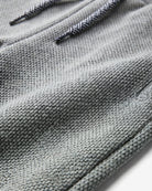 Close-up of a gray textured knit fabric with black and white patterned drawstrings.