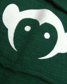 Close-up of green fabric with a playful monkey face design, ideal for casual wear alongside the Terracotta Baseball Tee.