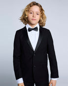Boy wearing a tuxedo from the Tuxedo Suit Bundle 3-Piece Set, featuring a sleek jacket, bow tie, and dress shirt.