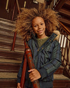 Black Watch Tartan City Transit Coat on a child standing on stairs, smiling and holding a railing.