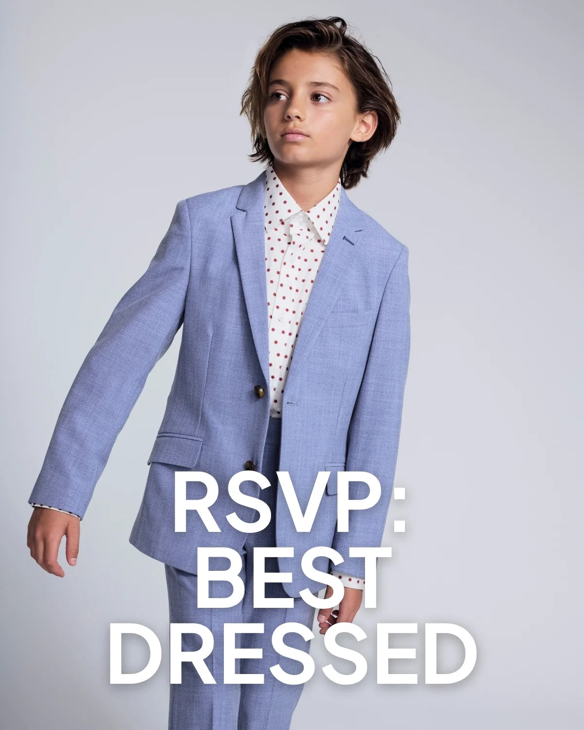Child wearing a light blue suit with a white shirt featuring red patterns on a gray background.