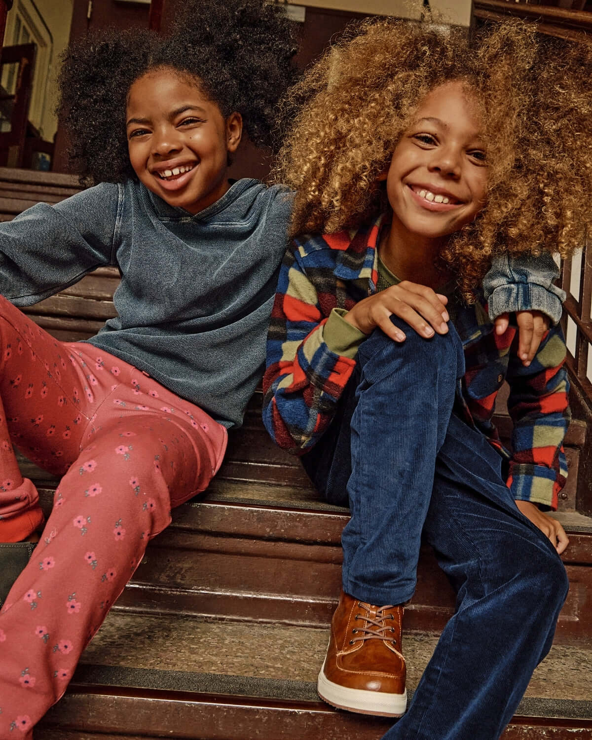 Two children smiling while sitting on stairs, wearing Navy Blue Club Pants and colorful tops.