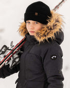 Stylish child wearing a Black Denali Down Coat while holding skis in a winter setting.