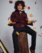 Boy wearing Old English Everyday Stretch Pants, playing with colorful autumn leaves on a wooden log.
