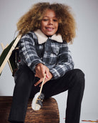 Child in a cozy plaid jacket, wearing Tweed Everyday Stretch Pants, enjoying a marshmallow treat.