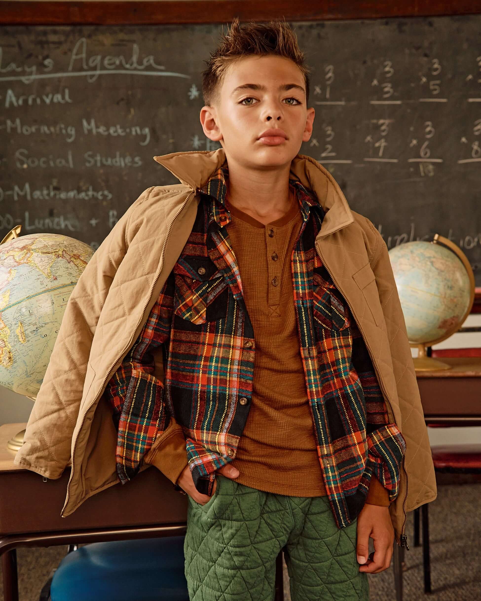 Boy wearing Khaki Flight Jacket with quilted material, paired with plaid shirt and stylish pants in a classroom setting.