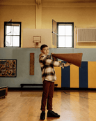 Boy wearing Lumber Plaid Glen Flannel Hoodie holding a megaphone in a gym with blue and yellow walls.