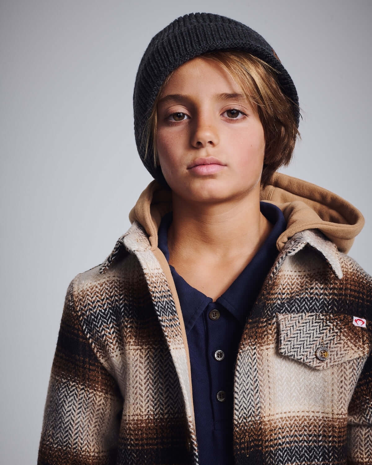 Lumber Plaid Glen Flannel Hoodie showcased by a young model wearing a beanie with a serious expression.