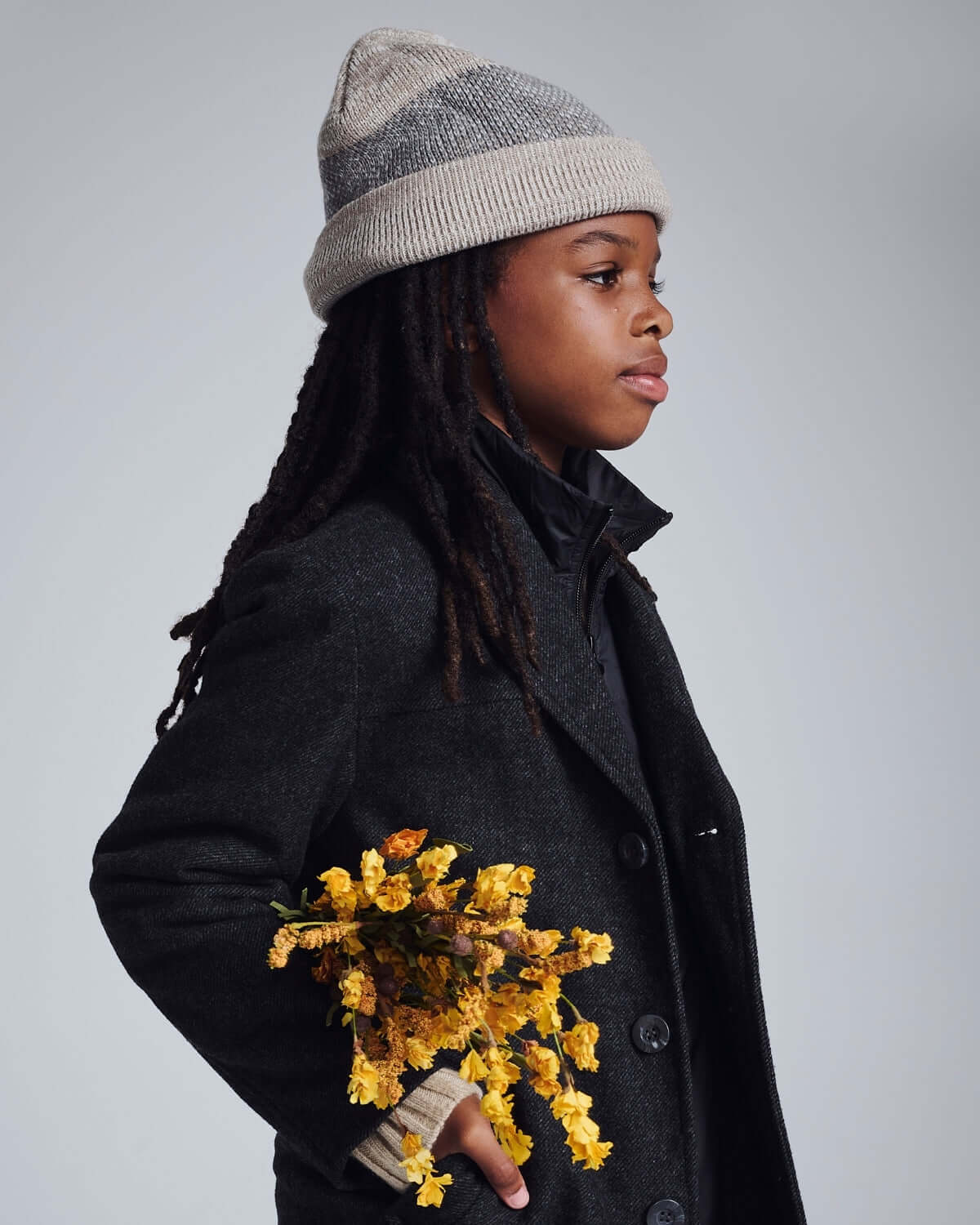 Heather Oatmeal Levi Hat worn by a child holding yellow flowers, showcasing style and versatility in fashion.