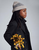 Heather Oatmeal Levi Hat worn by a child holding yellow flowers, showcasing style and versatility in fashion.