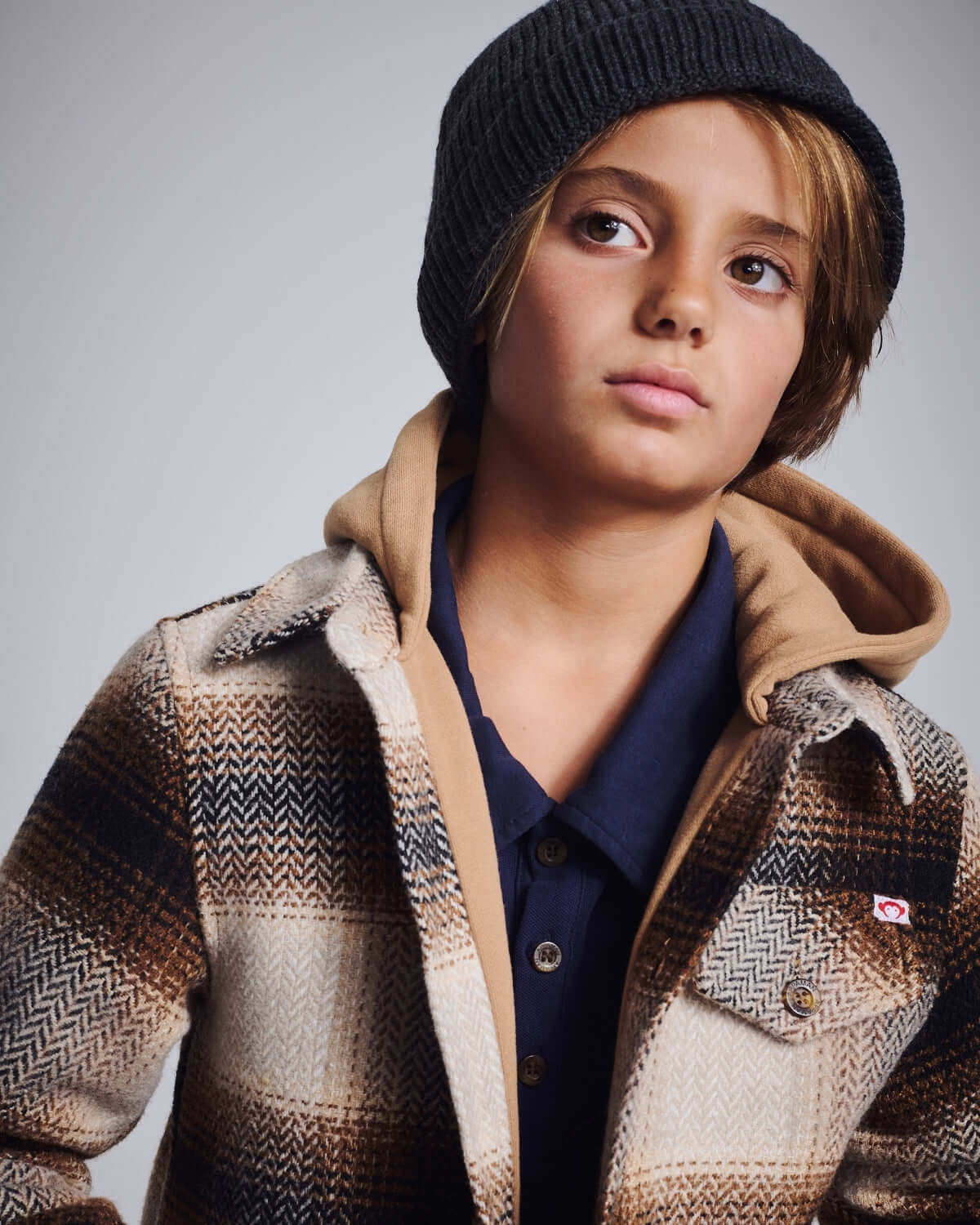 Child wearing a stylish Heather Black Masson Hat with a plaid jacket and hoodie.