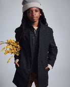 A child wearing the Black Tweed New City Overcoat, holding yellow flowers, showcasing cold-weather style.