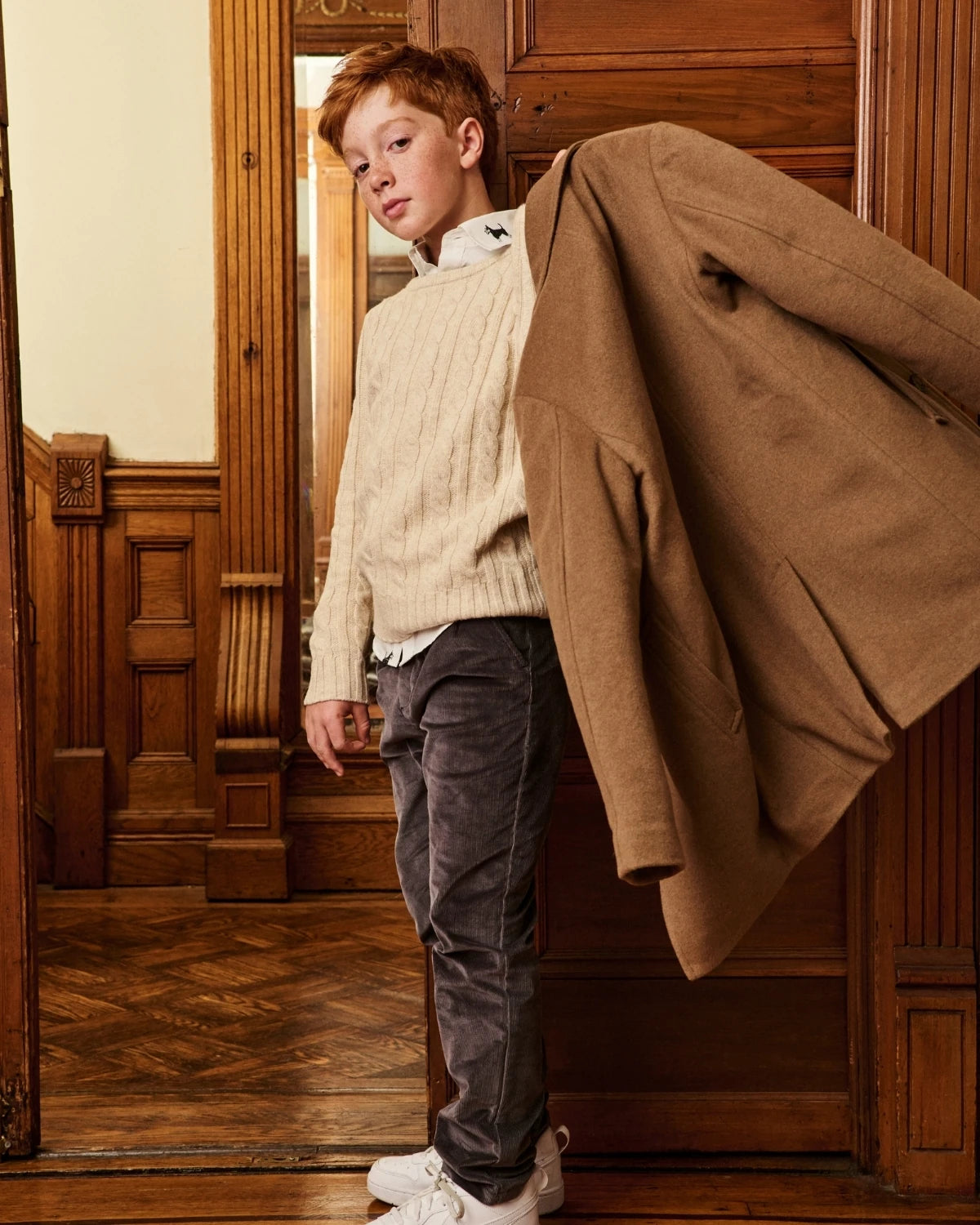 A boy wearing a camel wool coat, standing on a staircase. Appaman Fall/Winter 2026 collection.