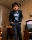 A young boy modeling the Gentleman's Plaid Stretchy Mod Suit with a stylish blue shirt and modern glasses.