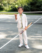 Boy wearing Papyrus Linen Beach Pants with a stylish blazer, holding a tennis racket and ball on a court.