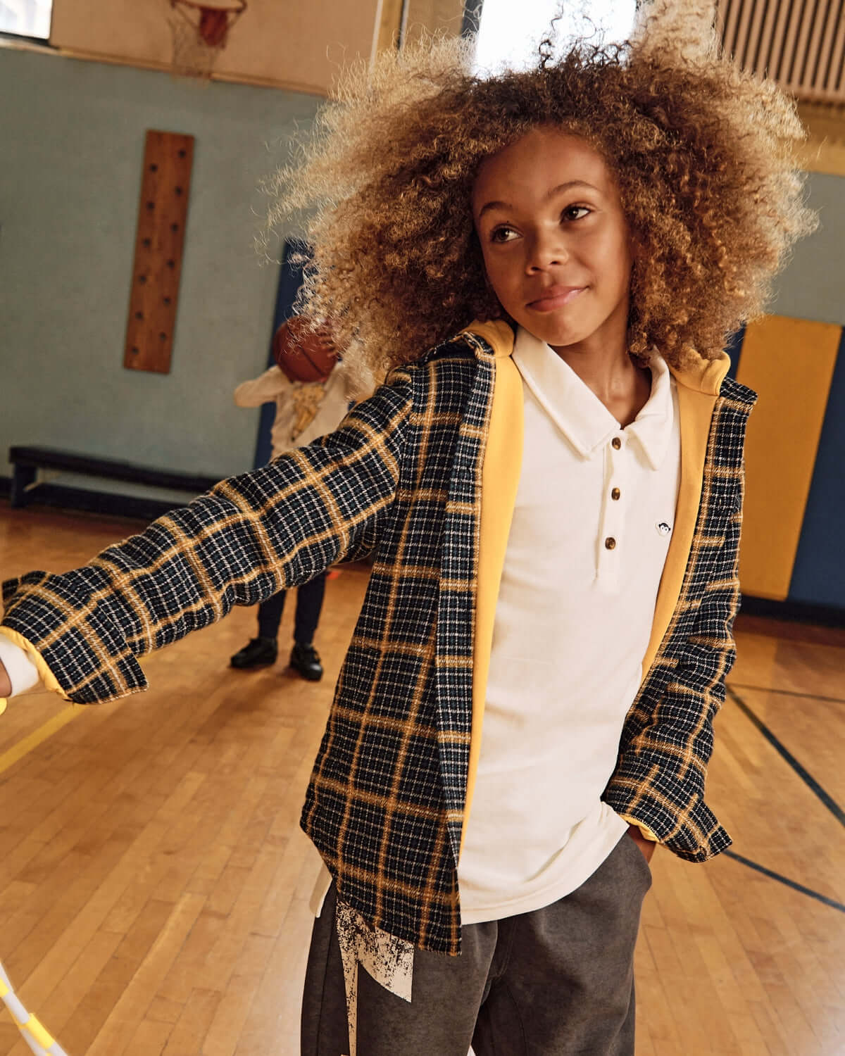 White Parker Polo worn by a boy in a gym, showcasing its lightweight and comfortable design for active kids.