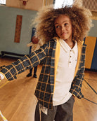 White Parker Polo worn by a boy in a gym, showcasing its lightweight and comfortable design for active kids.