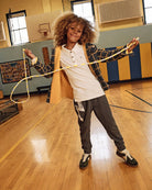 Child wearing a White Parker Polo, playing in a gym with a skip rope, showcasing casual style and comfortable fit.