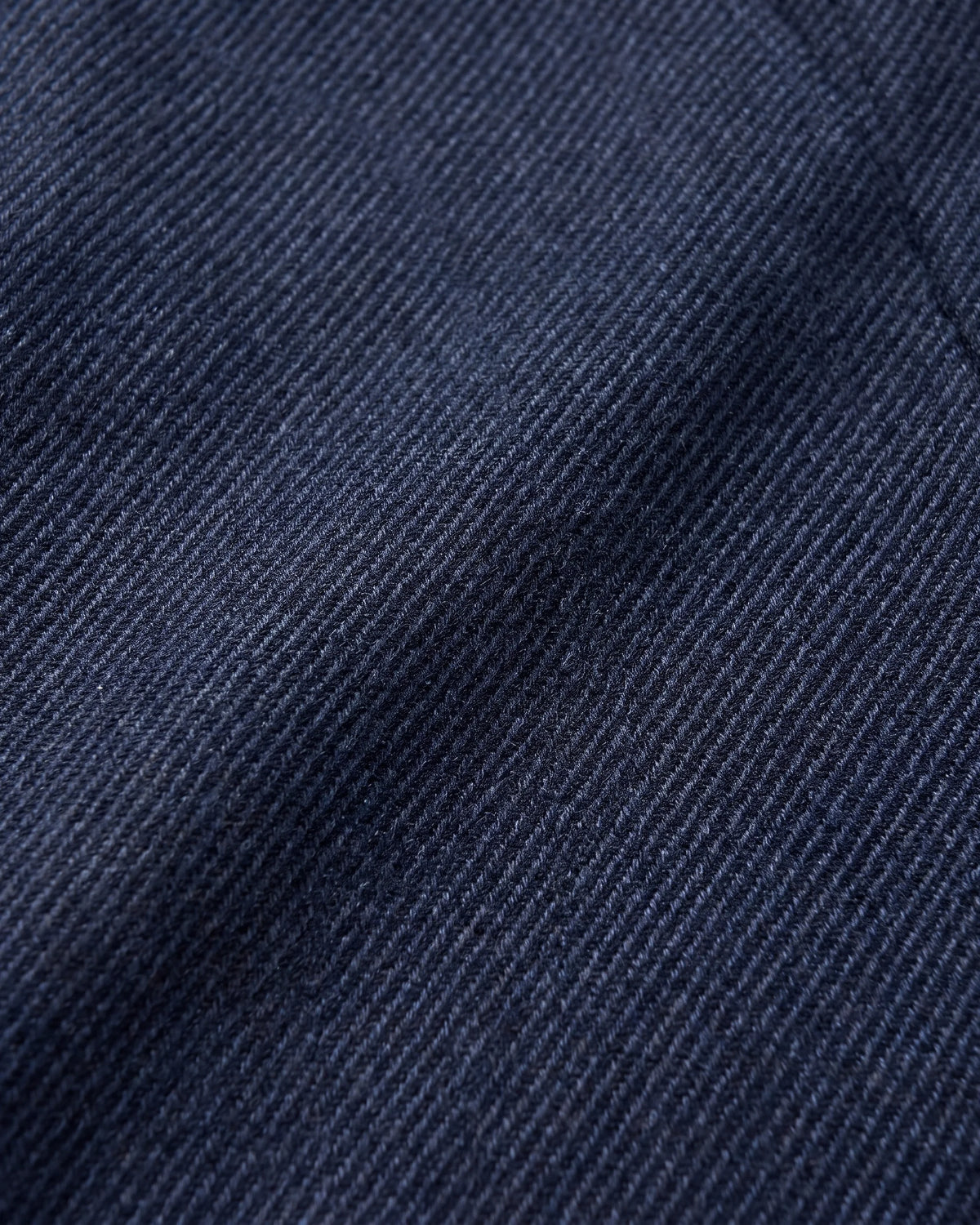 A close-up of dark navy blue textured fabric with a fine diagonal ribbed weave.