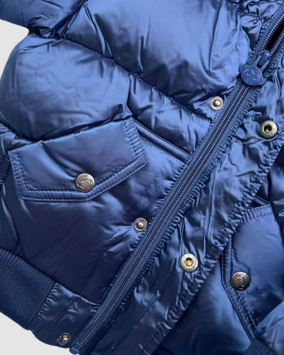 Close-up of Kids Navy Blue Puffy Coat showing zipper and pockets.