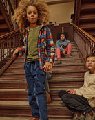Children wearing the Cherry Blue Check Snow Fleece Shirt and stylish outfits on wooden stairs.