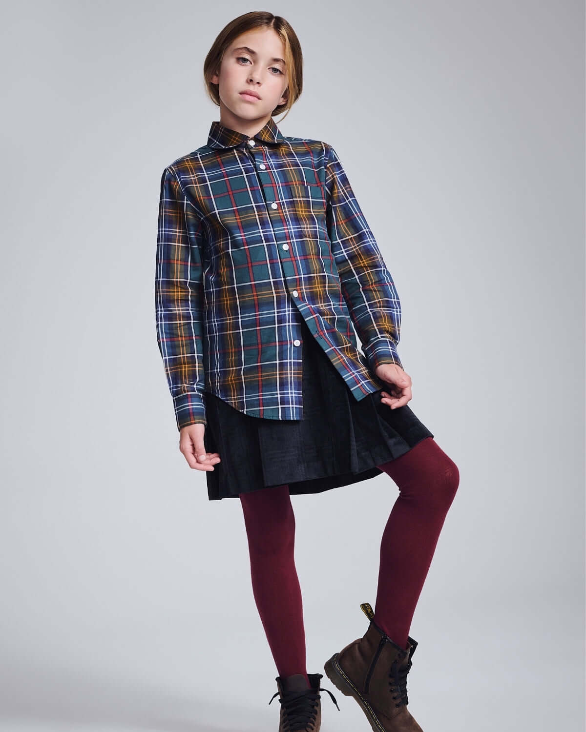 Girl wearing Lakeside Plaid Standard Button Down shirt with a skirt and tights, showcasing a stylish and comfortable look.