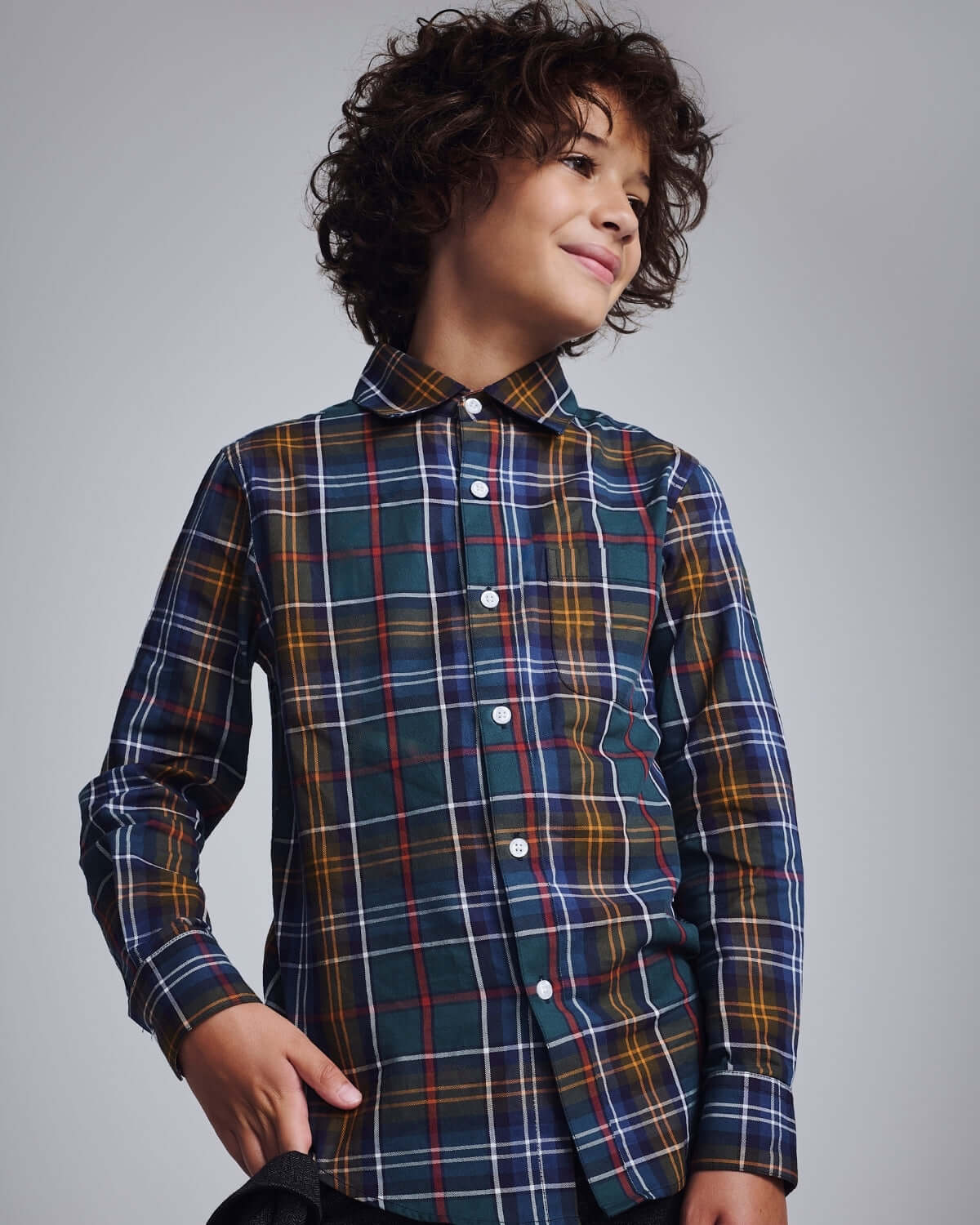 Lakeside Plaid Standard Button Down shirt on a smiling boy with curly hair, showcasing a colorful plaid pattern.