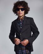 Boy wearing a Black Herringbone Stretchy Mod Suit with sunglasses and a plaid shirt.