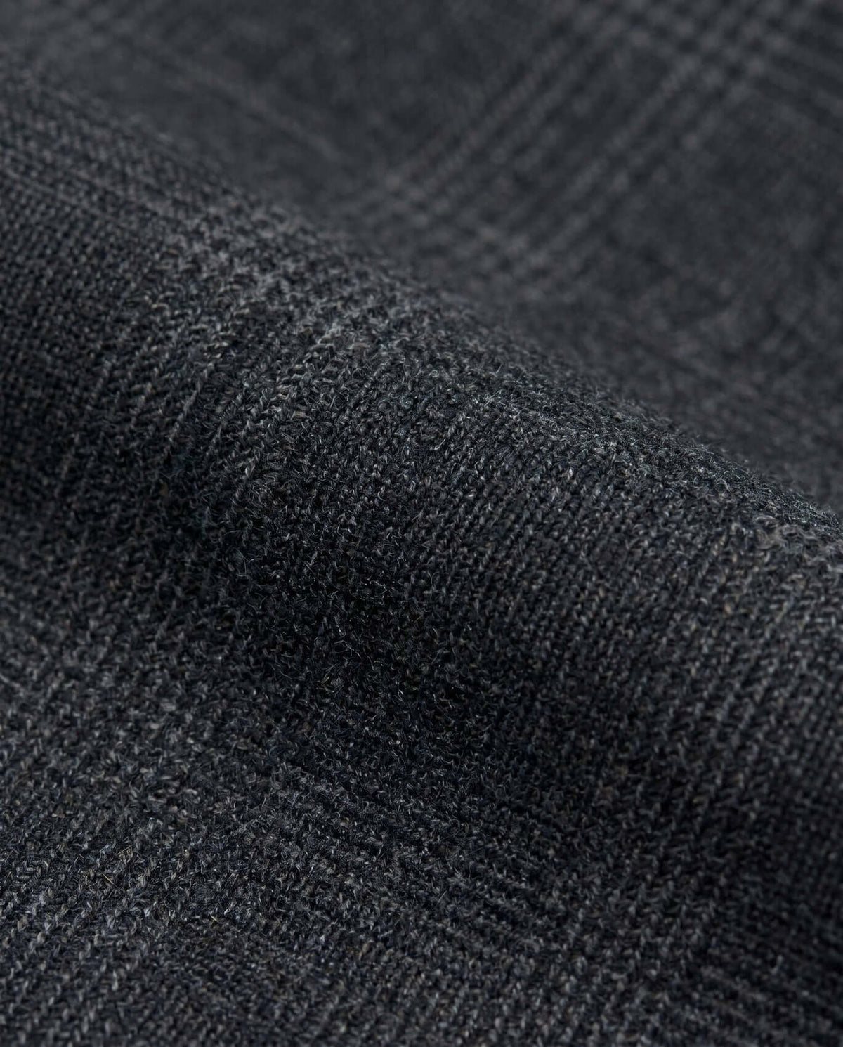 Close-up of Black Isle Tartan Stretchy Mod Suit fabric showcasing a textured dark plaid pattern.