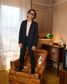 Black Herringbone Stretchy Suit Pants worn by a child in a stylish living room setting.