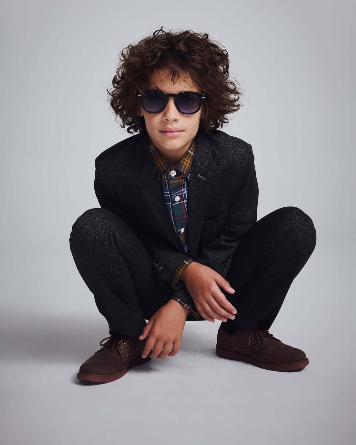 Black Herringbone Stretchy Suit Pants worn by a stylish kid with sunglasses and a plaid shirt.