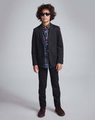 Black Herringbone Stretchy Suit Pants worn by a stylish boy with curly hair and sunglasses.