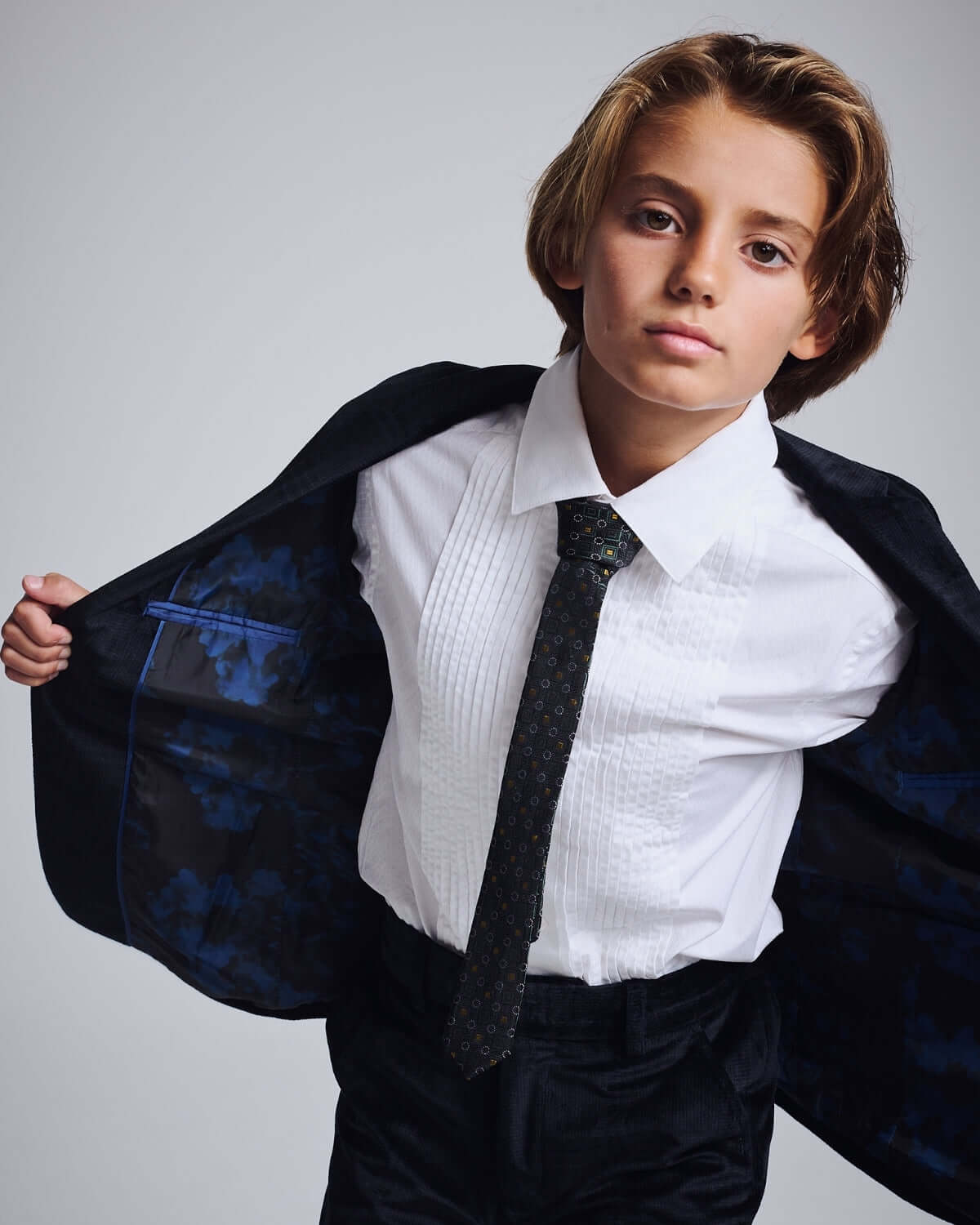 Kid wearing a Midnight Velvet Plaid Blazer with a white shirt and tie, showcasing sharp style and elegant tailoring.