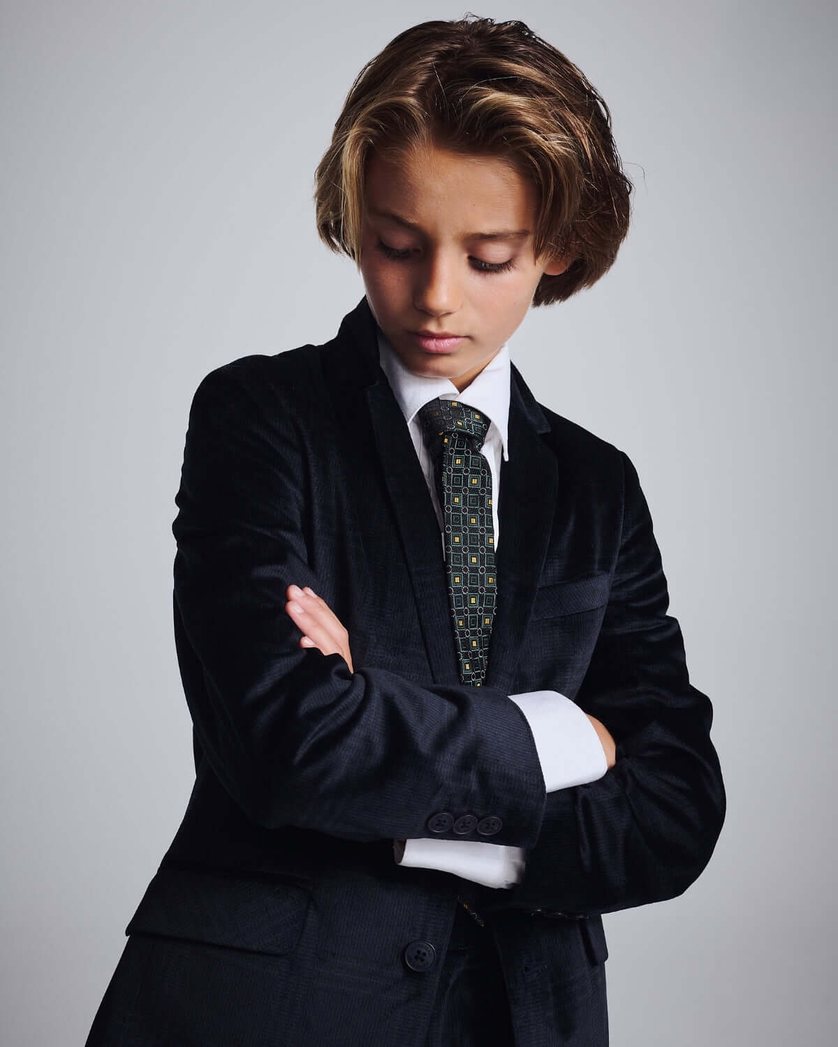 Child wearing a Midnight Velvet Plaid Blazer, stylishly posed with arms crossed, showcasing elegance and sophistication.