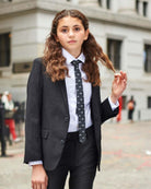 Girl wearing Black Suit Pants with a blazer and tie in an urban setting.