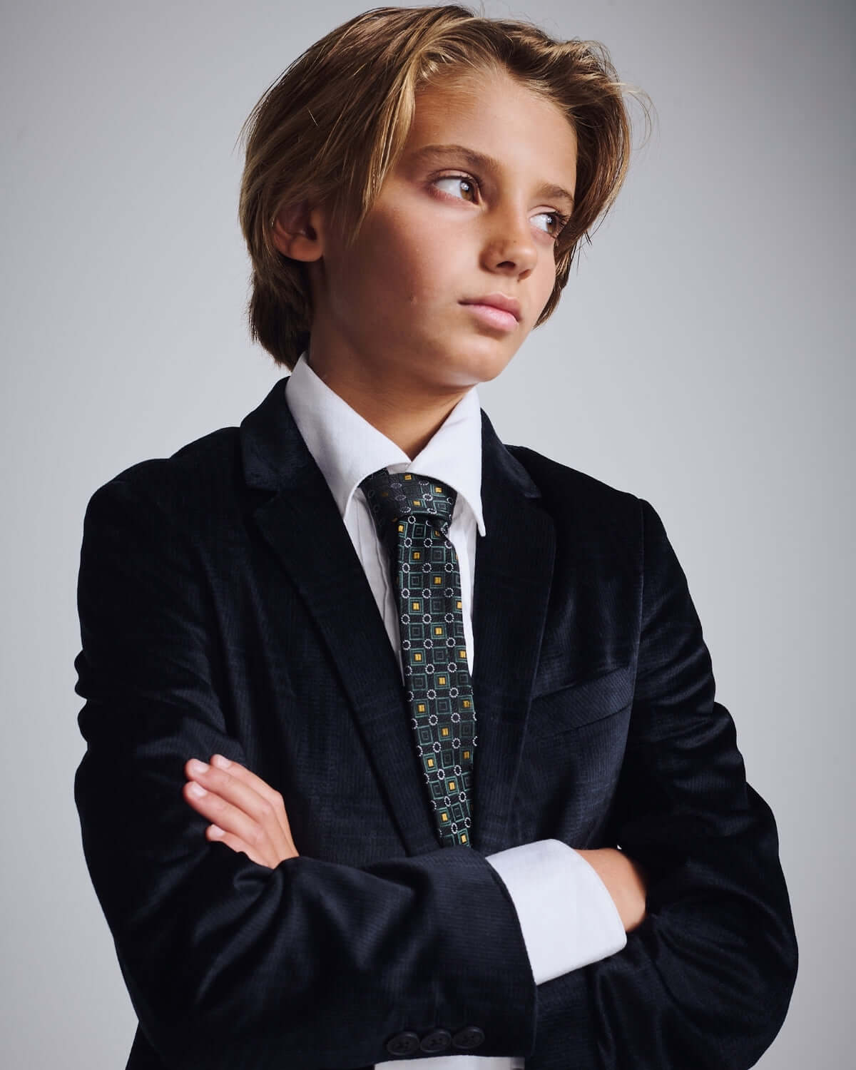 Boy in a black suit wearing a Gold Spruce Tie, showcasing fine tailoring and style for special occasions.